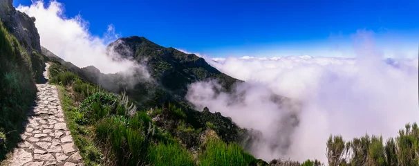 Gordijnen Hiking activity in Madeira island rocky mountains. Trail for Pico Ruivo highest point passing in the clouds © Freesurf