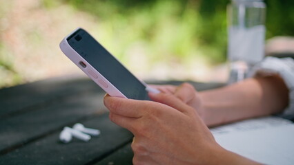Woman hands typing mobile phone at nature close up. Unrecognized girl texting