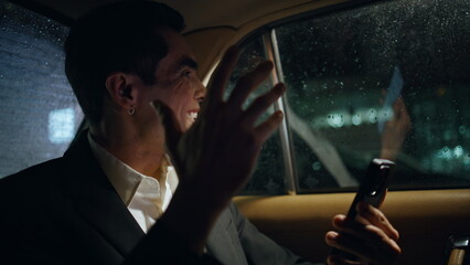 Excited boss rejoicing cellphone night car closeup. Happy businessman gesturing
