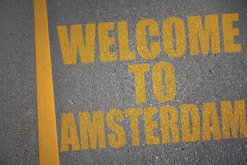 asphalt road with text welcome to Amsterdam near yellow line.