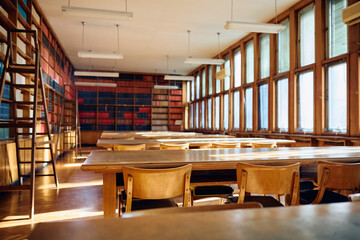 High school library with bookshelves, tables, chairs and no people.