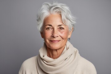 Portrait of chic beautiful gray-haired mature woman 50-60 years old in elegant clothes on gray background. An elderly woman smiles and looks at camera. Beautiful old age, cosmetology, face lifting