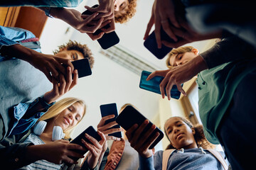 Fototapeta na wymiar Below view of group of teenagers using smart phone at high school.