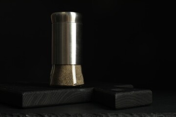Pepper shaker on black table. Space for text