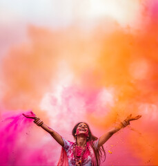 une jeune femme indienne, les bras en l'air, durant la fête des couleurs Holi