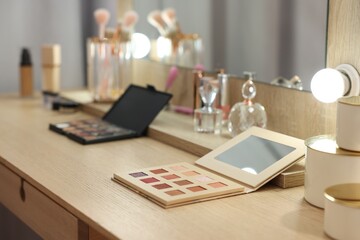 Cosmetic products on wooden dressing table in makeup room