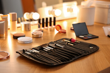 Set of makeup brushes and cosmetics on wooden table