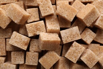 Different types of brown sugar as background, top view