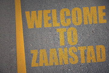 asphalt road with text welcome to Zaanstad near yellow line.