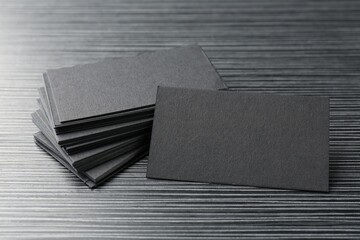 Blank black business cards on wooden table, closeup. Mockup for design