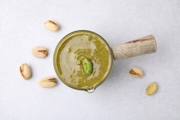 Tasty pistachio cream and nuts on white table, top view