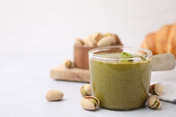 Tasty pistachio cream and nuts on light table, closeup. Space for text