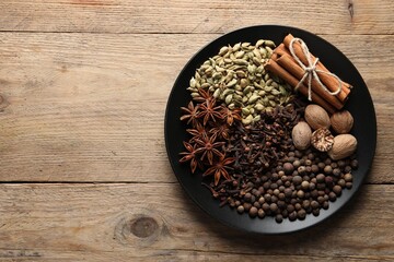 Different spices and nuts on wooden table, top view. Space for text