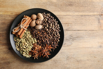 Different spices and nuts on wooden table, top view. Space for text