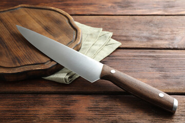 One sharp knife and board on wooden table, closeup