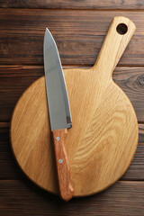 Knife and board on wooden table, top view