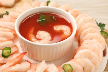 Tasty boiled shrimps with cocktail sauce, chili and parsley on table, closeup