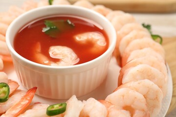 Tasty boiled shrimps with cocktail sauce, chili and parsley on table, closeup