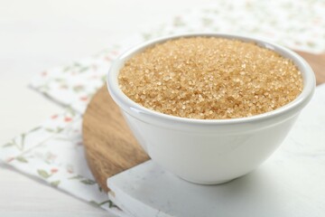 Brown sugar in bowl on table, closeup. Space for text