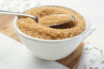 Brown sugar in bowl and spoon on table, closeup