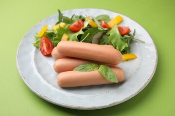 Delicious boiled sausages with salad on green