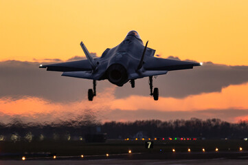 A Lockheed Martin F-35 Lightning II fifth generation fighter jet is ready to land during a beautiful sunset.  - obrazy, fototapety, plakaty