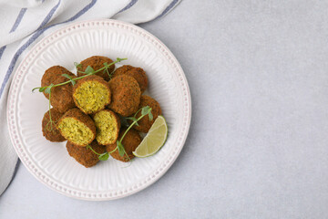 Delicious falafel balls, lime slice and microgreens on light table, top view. Space for text