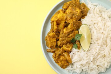 Delicious chicken curry with rice on yellow background, top view. Space for text