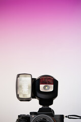 flash girado montado en cámara digital con espacio para texto y degradado rosa