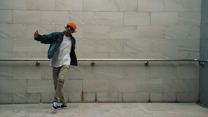 Asian smart hipster show energetic break dance with gray background at building while wearing...