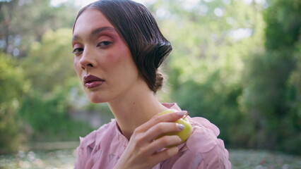 Obraz premium Closeup extraordinary model posing in green forest holding apple. Majestic fairy