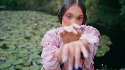 Obraz premium Mysterious girl posing camera waving hands on park pond close up. Majestic woman