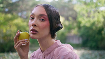 Mysterious woman looking camera holding apple close up. Fairy girl posing nature