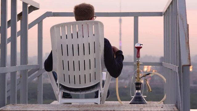 Guy smoking hookah and transposing it closer, checking heating on roof
