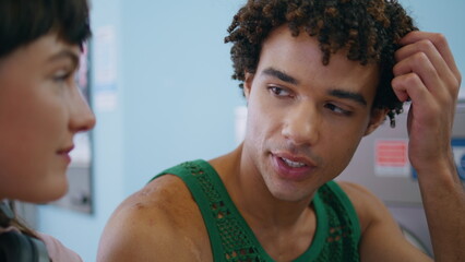 Hispanic guy talking girl in laundry service closeup. Handsome curly man chat