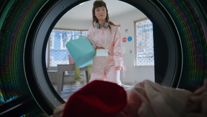 Casual girl taking laundry out machine closeup. Confused woman holding colored 