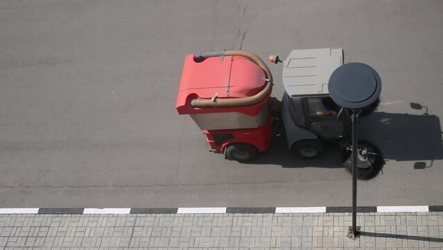 Sweeper cleans the street next to the sidewalk, above view