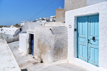 Old light blue wooden door against clear white wall in a narrow street of Pyrgos Kallistis village, Santorini. Greek Islands, European Vacation. Travel, holidays, relax, adventure.