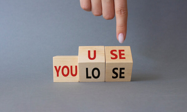 You use or lose symbol. Businessman hand points at cubes with words You lose or You use. Beautiful grey background. Business and You use or lose concept. Copy space