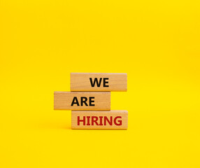 We are Hiring symbol. Concept words We are Hiring on wooden blocks. Beautiful yellow background. Business and We are Hiring concept. Copy space.