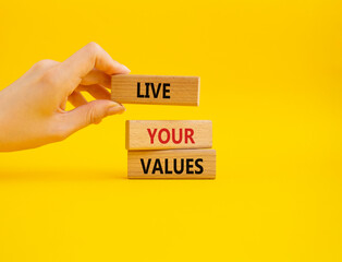 Live your values symbol. Concept words 'Live your values' on wooden blocks. Beautiful yellow background. Businessman hand. Business and Live your values concept. Copy space.