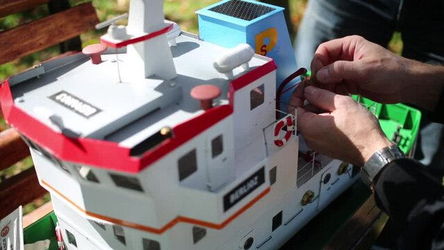 The man fastens a lifeboat on ship model near Big Putyaevsky Pond