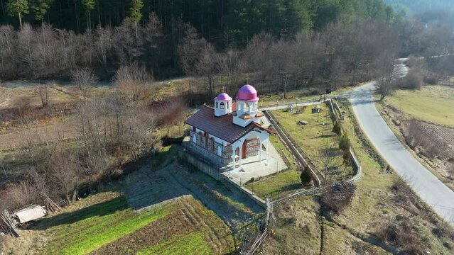Drone flies away from a an orthodox Saint Cosmas and Damian Chapel  near Dobrinishte, revealing its surroundings. 