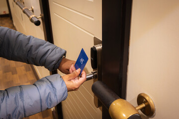 Closeup hand of young latin woman using a keycard to unlock electronic sensor of hotel door....