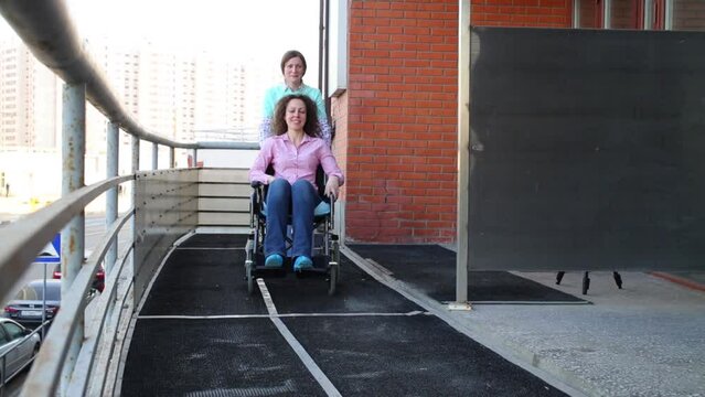 Nurse and patient in a wheelchair go on the balcony