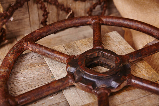Vintage Rusted Metal Wheel on Weathered Wood with Industrial Chain Background