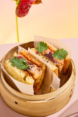 Asian sando sandwich with tuna and spicy sauce, presented in a bamboo steamer amidst abstract floral art