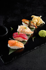Classic nigiri sushi with salmon, tuna, eel, and shrimp on a black slate