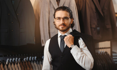 Portrait businessman in classic vest puts on suit jacket in shop store clothes for men