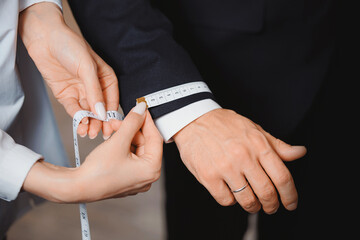 Taking measurements on man sleeve for sewing suit in luxury atelier classic menswear